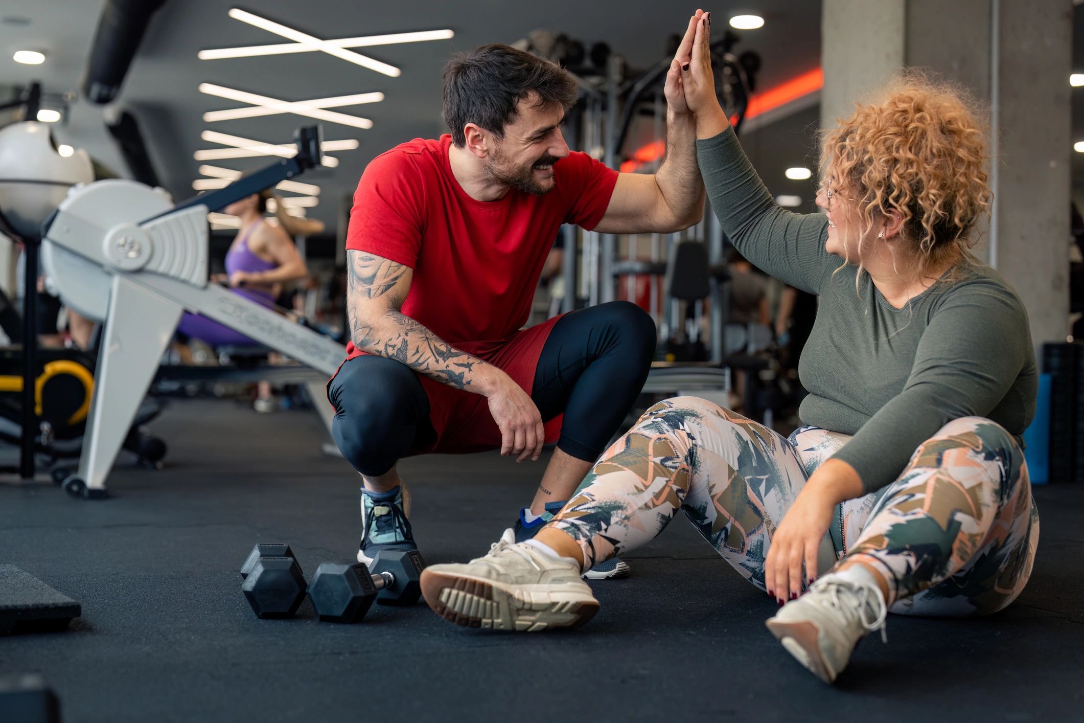 Coach and client celebrating progress with a high-five in the gym